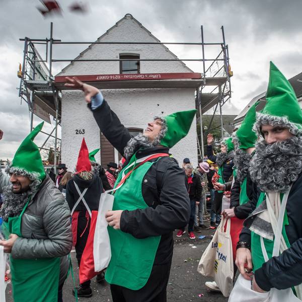 Als Zwerge verkleidete Männer werfen im Hitdorfer Karnevalszug Kamelle.