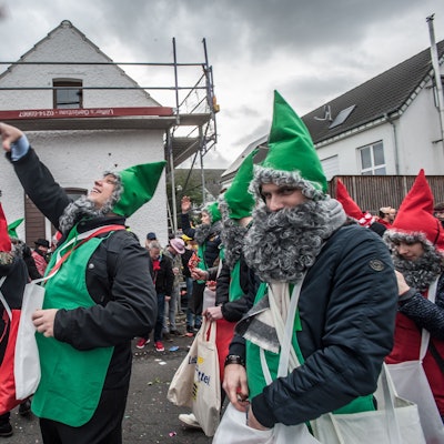 Als Zwerge verkleidete Männer werfen im Hitdorfer Karnevalszug Kamelle.