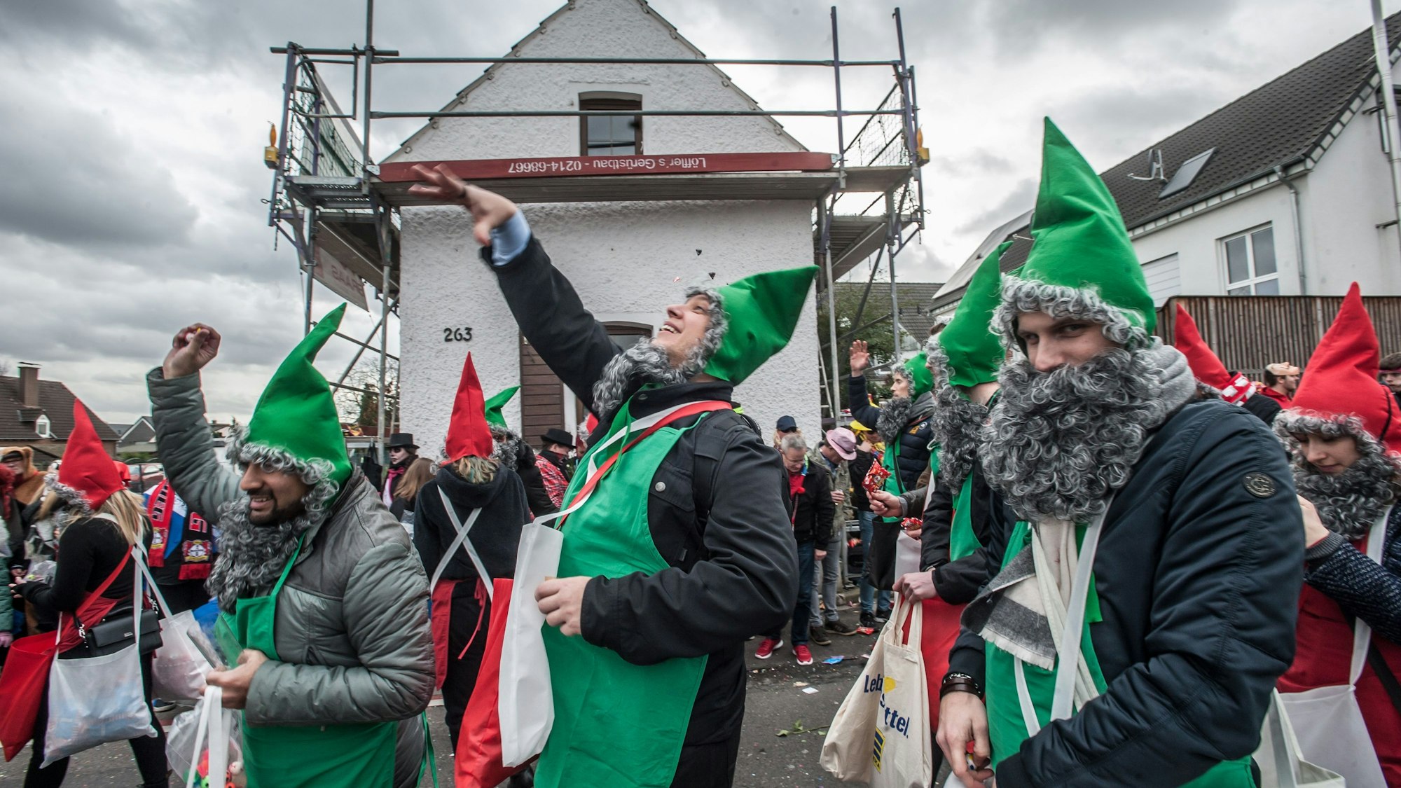 Als Zwerge verkleidete Männer werfen im Hitdorfer Karnevalszug Kamelle.