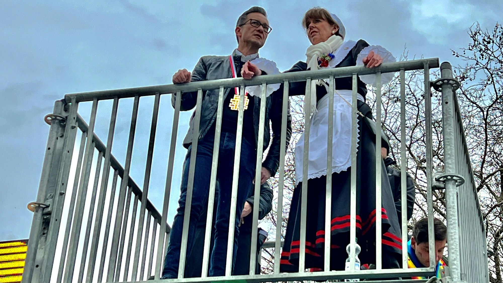 Polizeipräsident Falk Schnabel und Oberbürgermeisterin Henriette Reker stehen auf einer Aussichtsplattform vor der Unimensa und beobachten die Party auf den Uniwiesen.