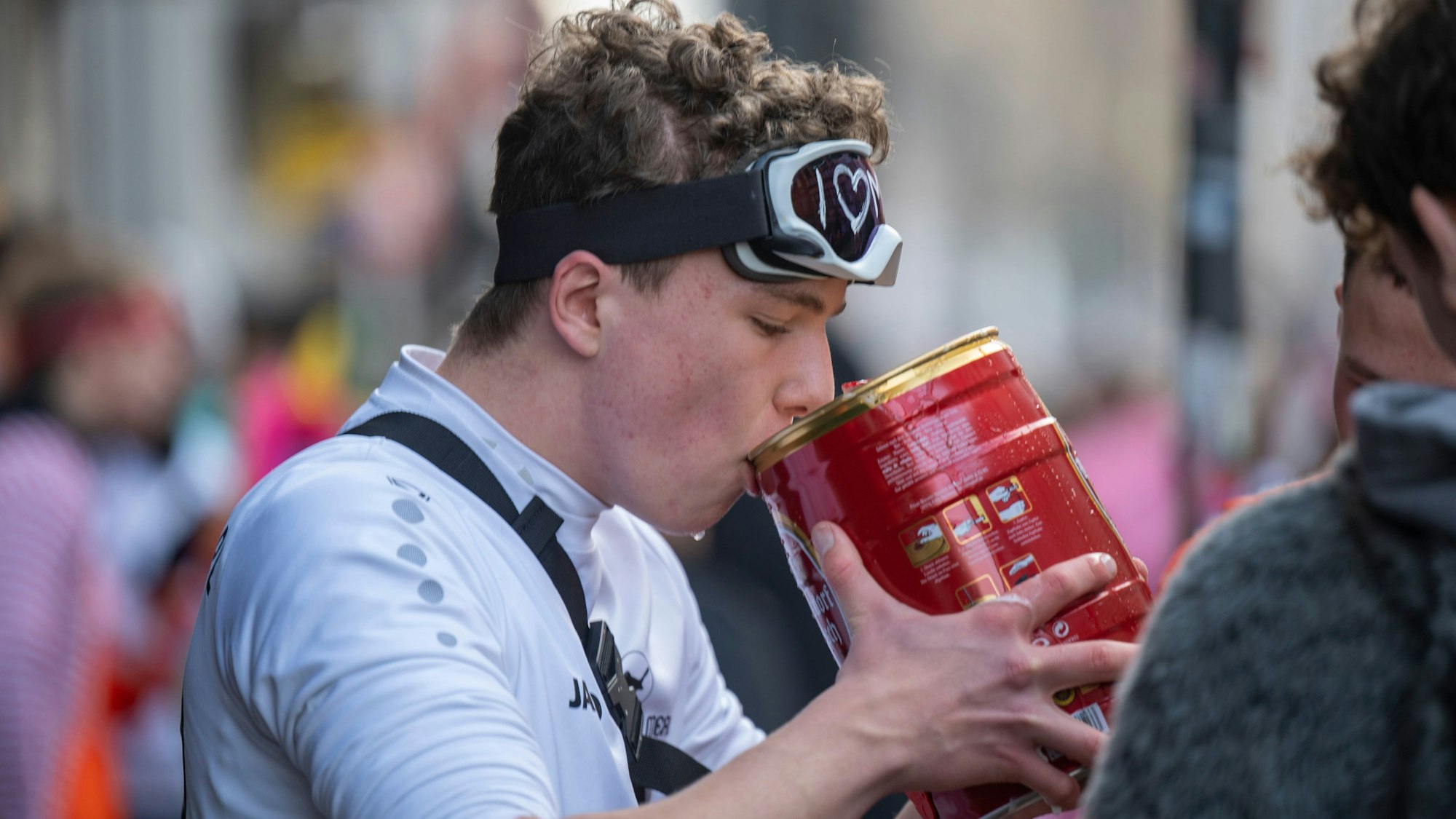 Ein junger Mann nimmt ein Fässchen Kölsch zum Mund und trinkt davon.