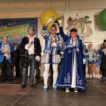 Das Prinzenpaar Mark und Tanja heben den symbolischen Rathausschlüssel hoch, neben ihnen steht auf der Bühne der Wolf kostümierte Bürgermeister Frank Steffes.