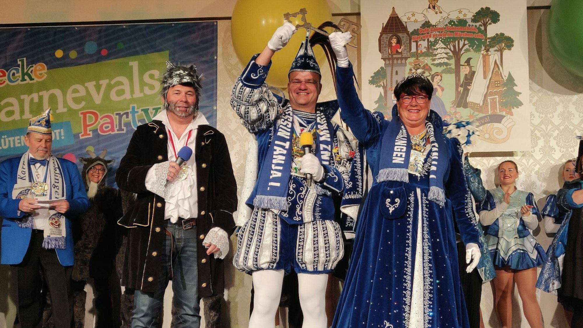 Das Prinzenpaar Mark und Tanja heben den symbolischen Rathausschlüssel hoch, neben ihnen steht auf der Bühne der Wolf kostümierte Bürgermeister Frank Steffes.