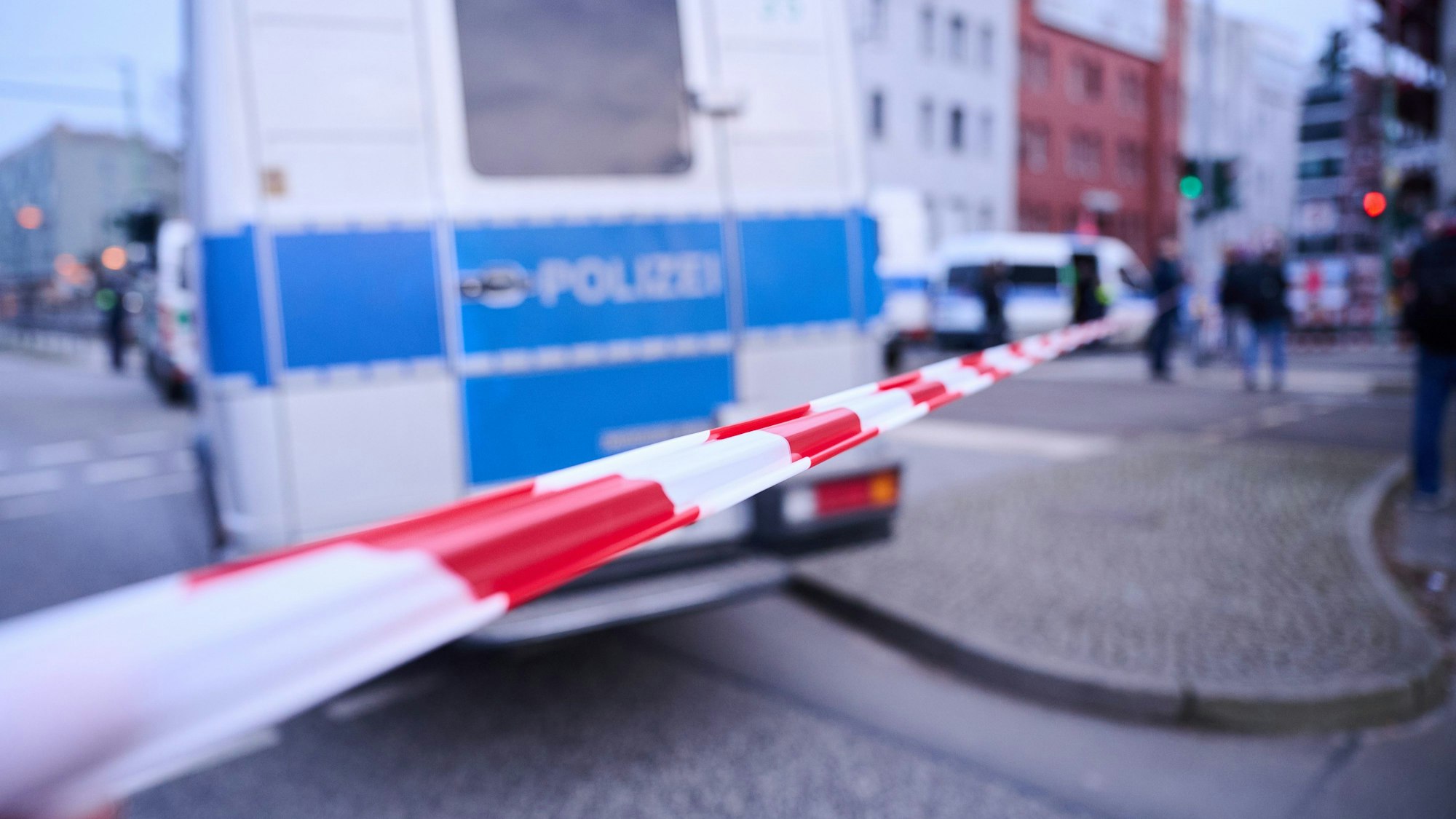 Absperrband vor einem Einsatzfahrzeug der Polizei.