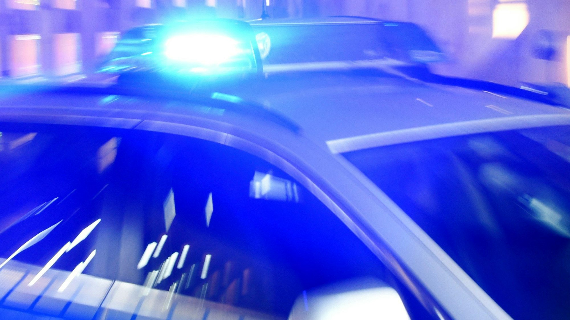 Ein Streifenwagen der Polizei steht mit eingeschaltetem Blaulicht auf der Straße.