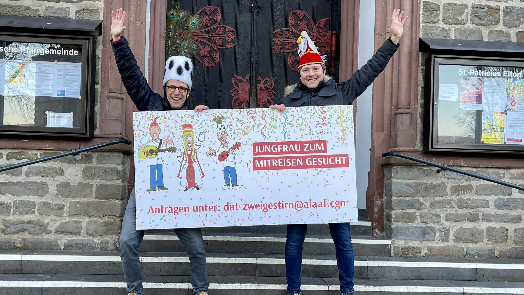 Es sind die beiden Männer zu sehen, die ein Schild mit der Aufschrift „Jungfrau zum mitreisen gesucht“ hochhalten.