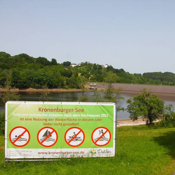 Vor dem Kronenburger See steht ein großes Schild, auf dem steht: „Aufgrund technischer Arbeiten nach dem Hochwasser 2021 ist eine Nutzung der Wasserfläche in diesem Jahr leider nicht gestattet.“