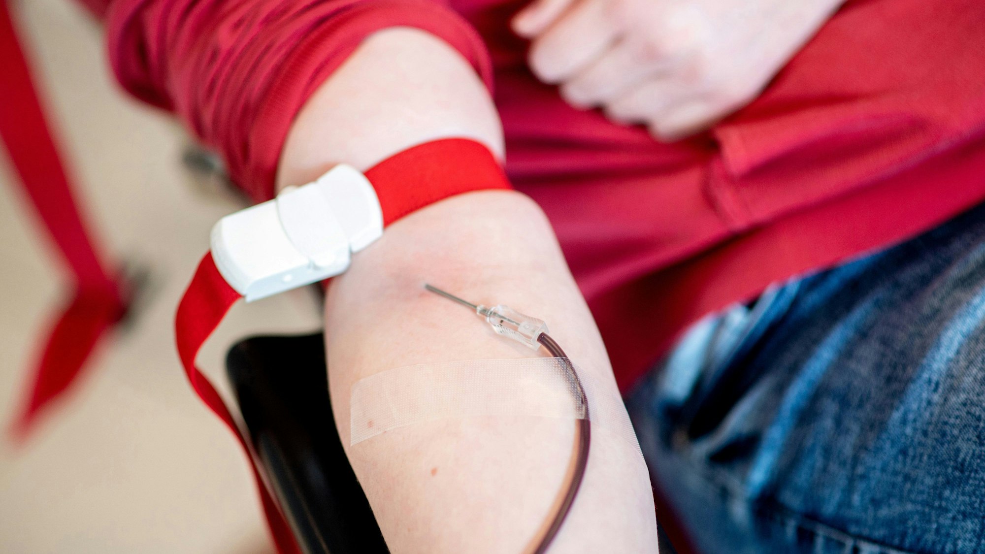 Blut läuft vom Arm einer Spenderin durch eine Nadel in einen Schlauch.