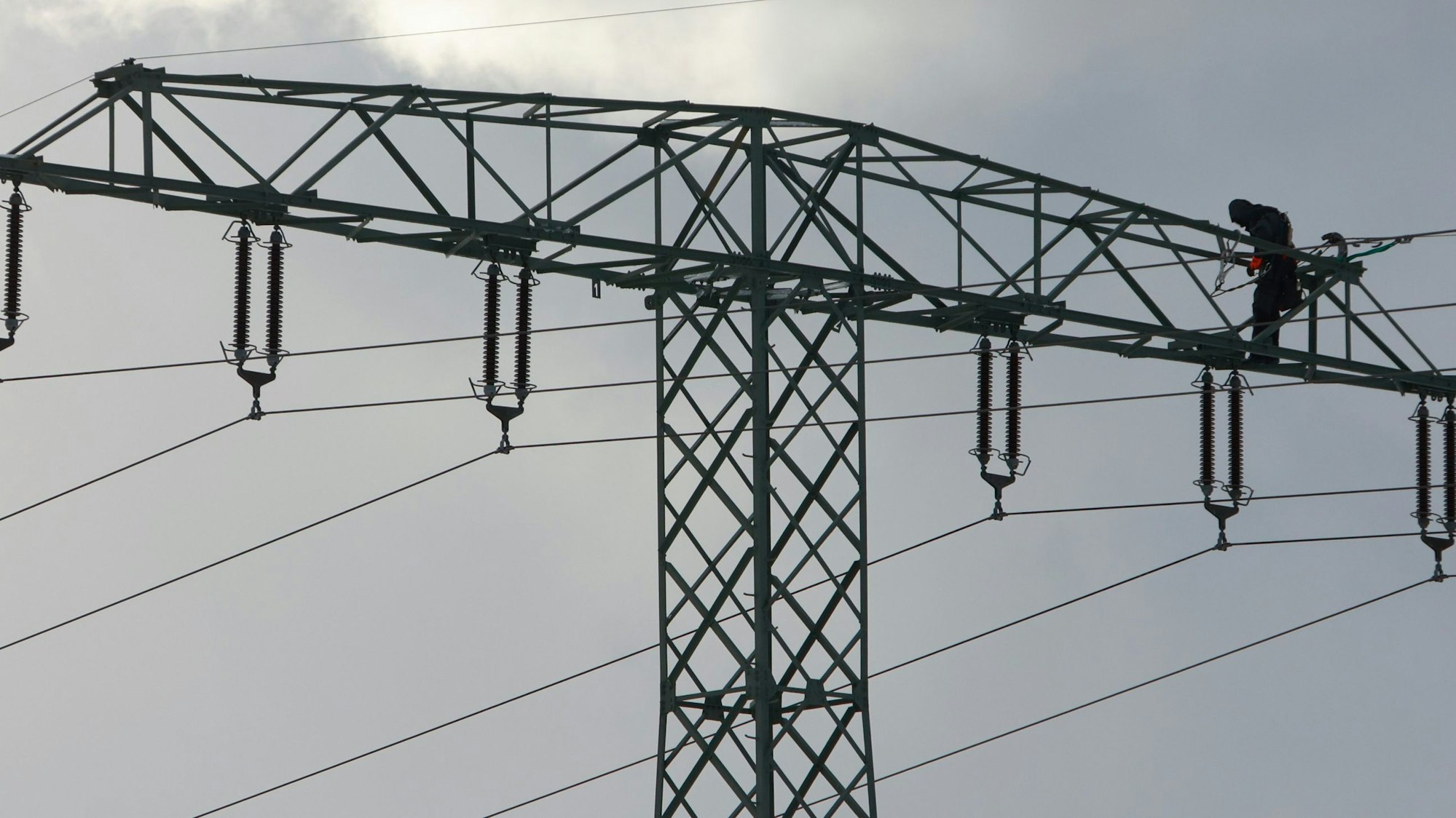 Ein Mann steht auf einem Strommast.