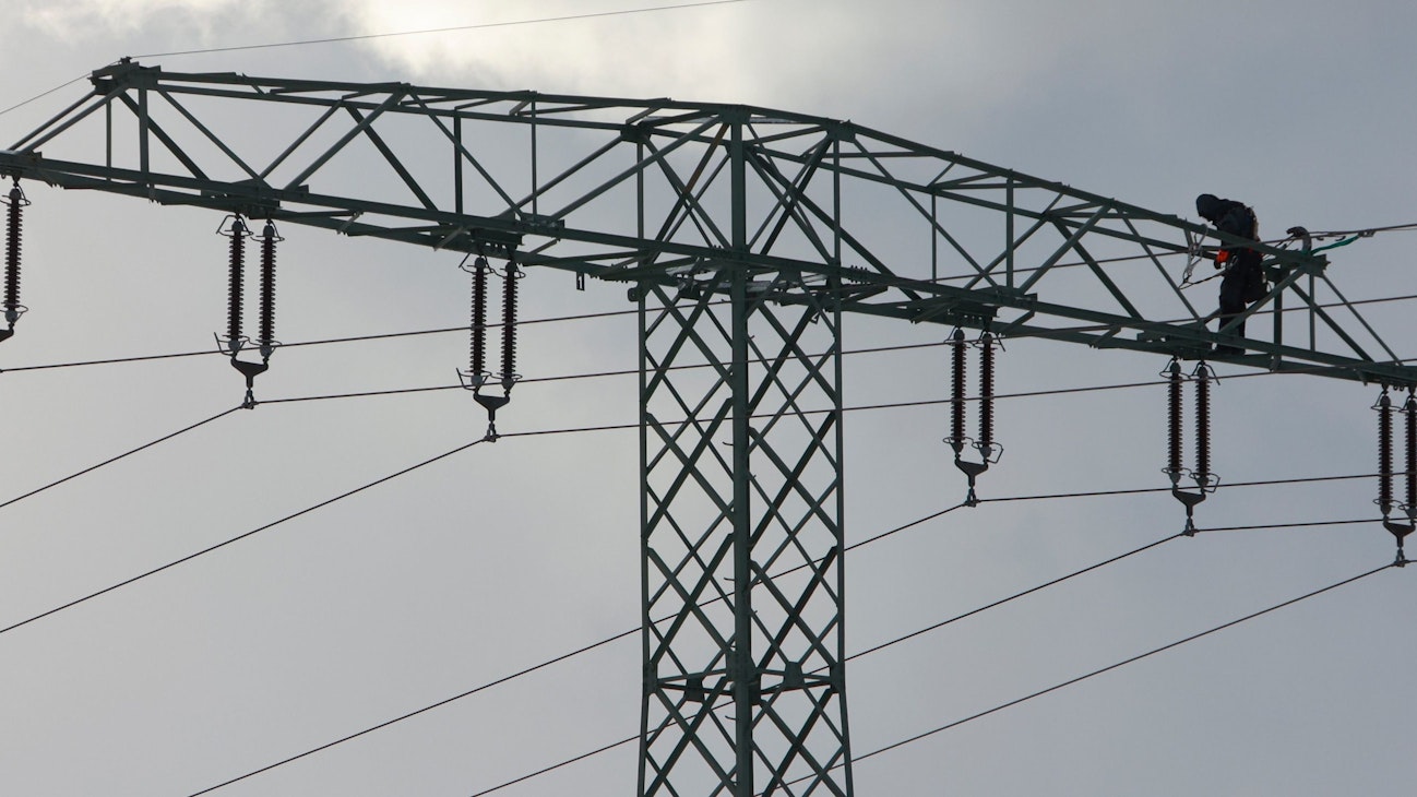 Ein Mann steht auf einem Strommast.