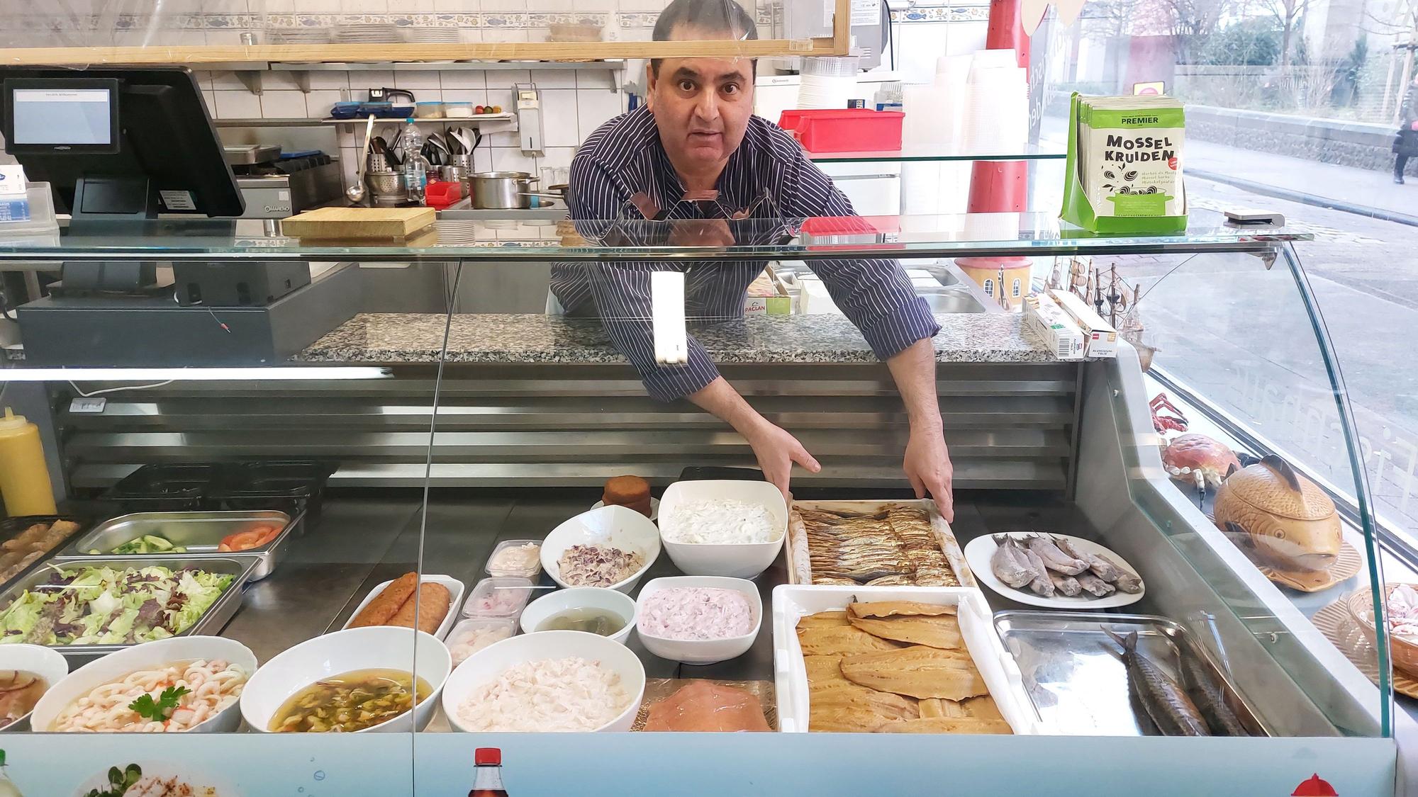 Fischhändler Kumar legt Platten mit Fisch in die Theke seines Geschäftes.