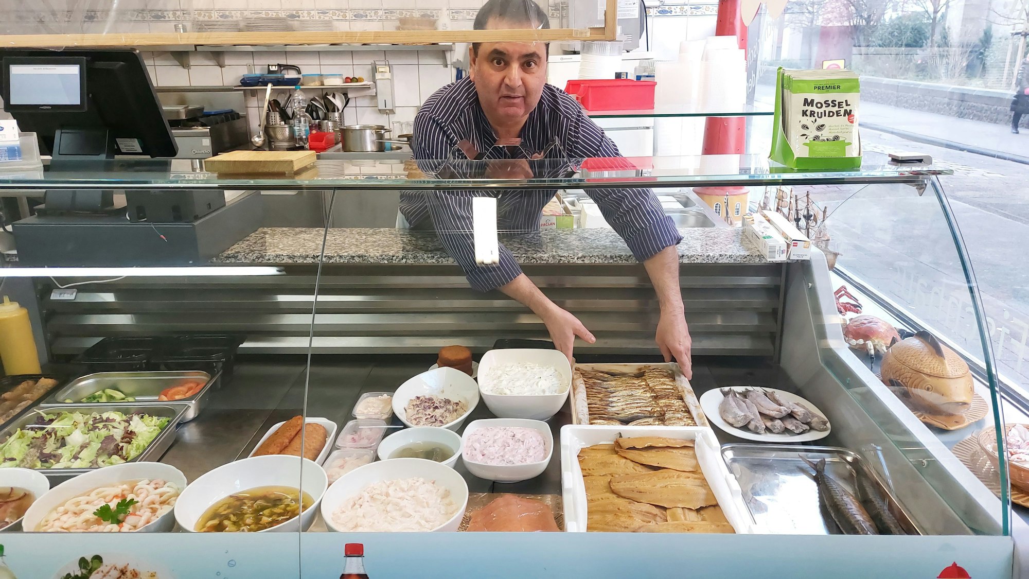 Fischhändler Kumar legt Platten mit Fisch in die Theke seines Geschäftes.