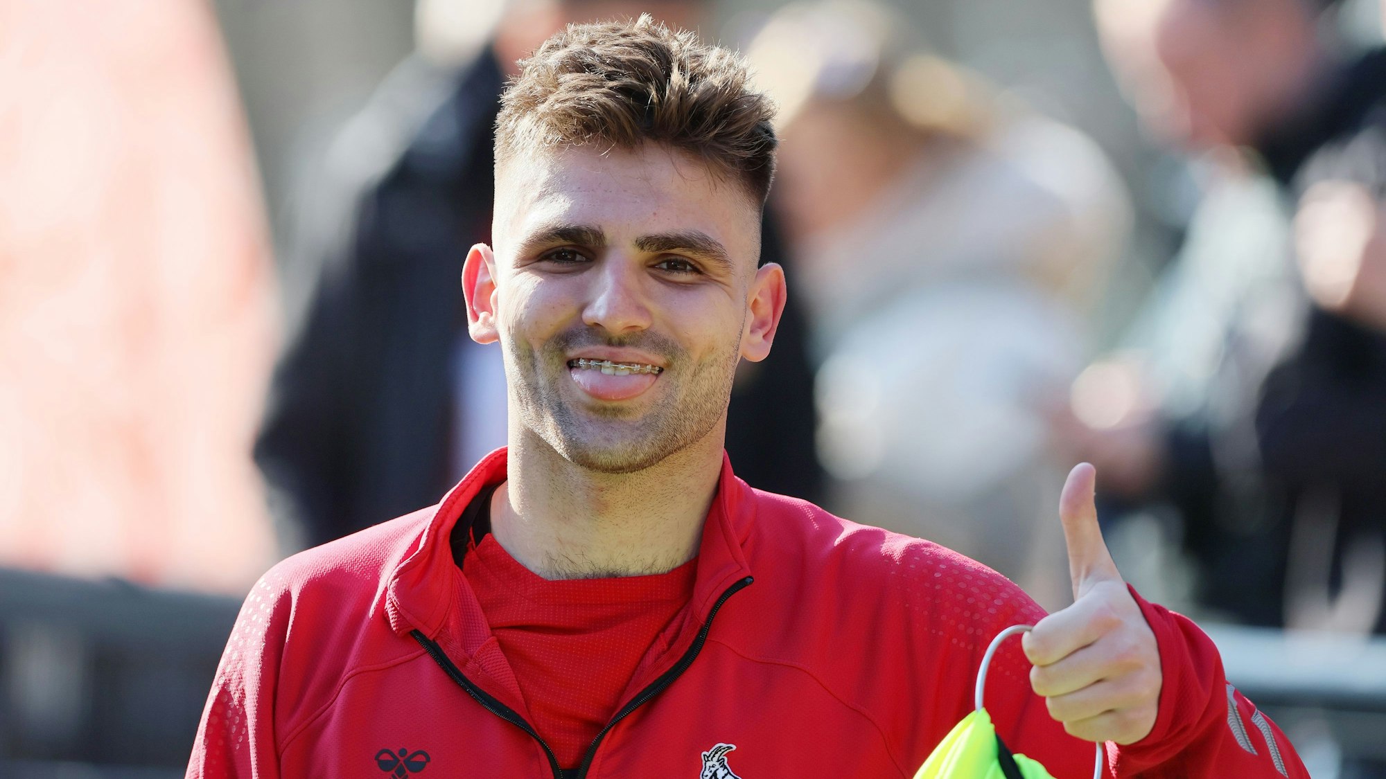 Nikola Soldo auf dem Trainingsplatz des 1. FC Köln. Der Spieler signalisiert seine Bereitschaft mit dem „Daumen hoch“-Zeichen.