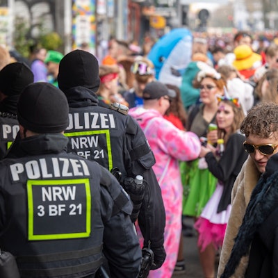 Polizeibeamte stehen inmitten von Feiernden auf einer Straße.