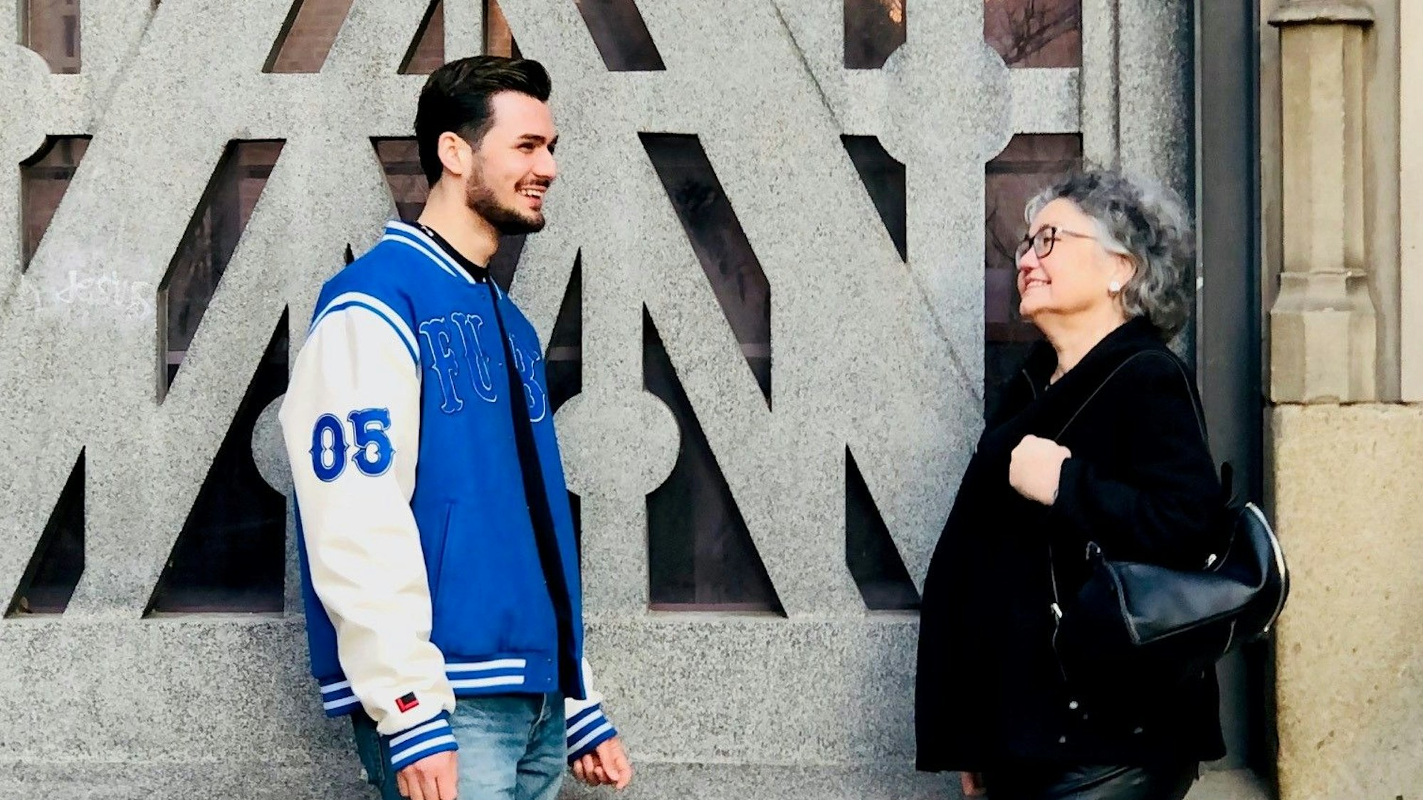 Milad, 18, aus dem Iran und seine ehrenamtliche Vormundin Hanna Dirk aus Bensberg stehen vor der St. Mauritius Kirche in Köln.