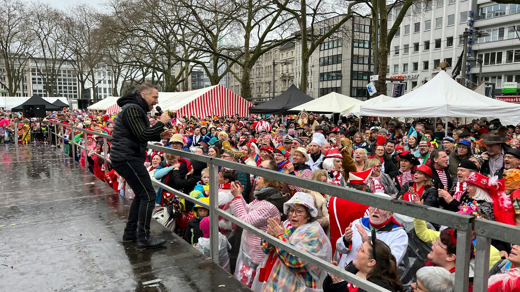Ein Mann singt auf einer Bühne vor vielen Menschen.