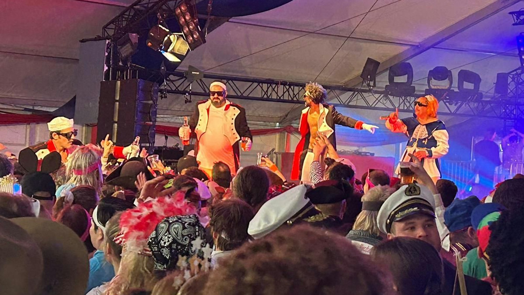 Verkleidete Jecke verteilen von der Bühne aus Getränke.