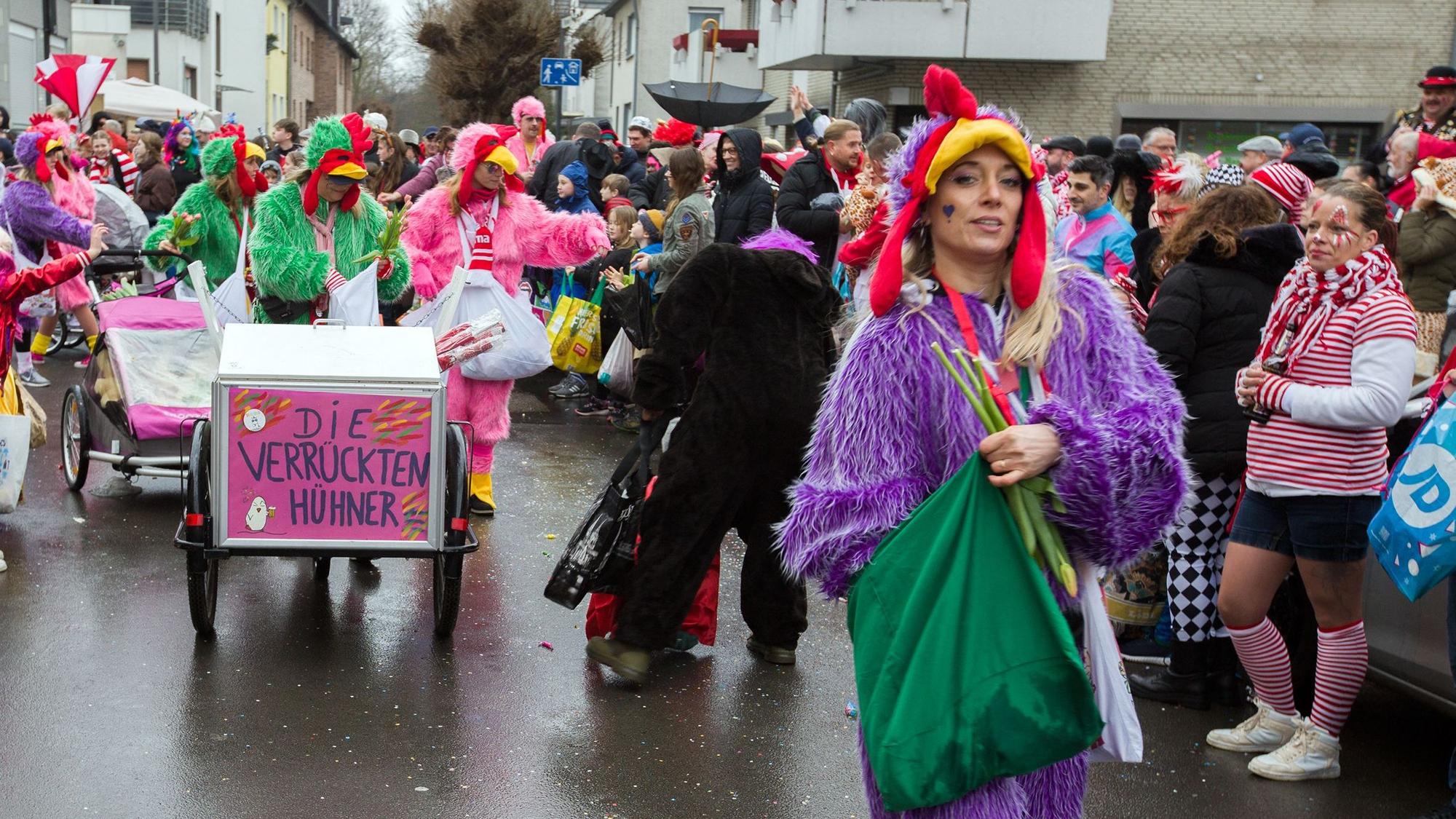Mehrere Frauen verteilen Kamelle an die Menschen am Straßenrand.