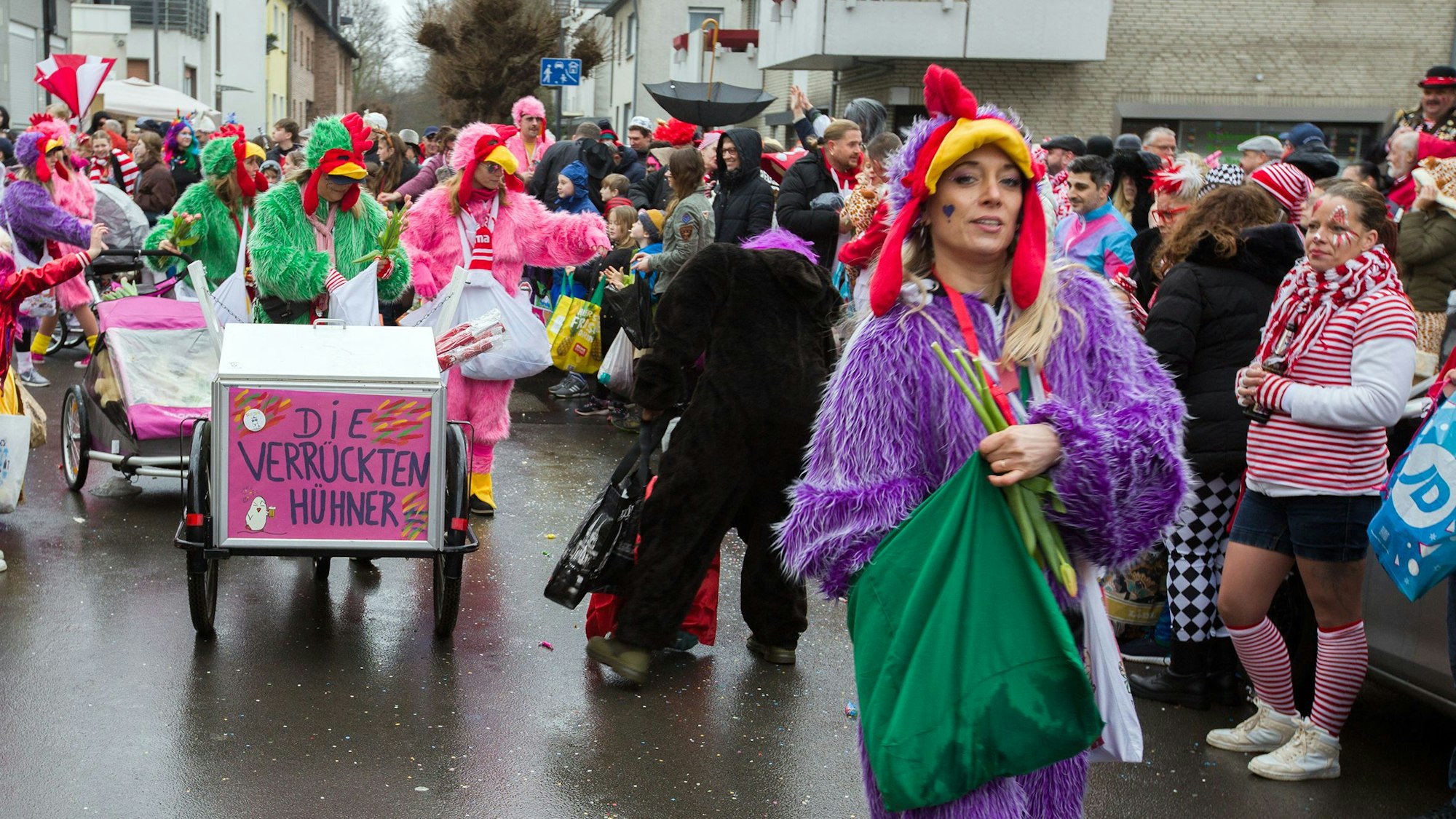 Mehrere Frauen verteilen Kamelle an die Menschen am Straßenrand.