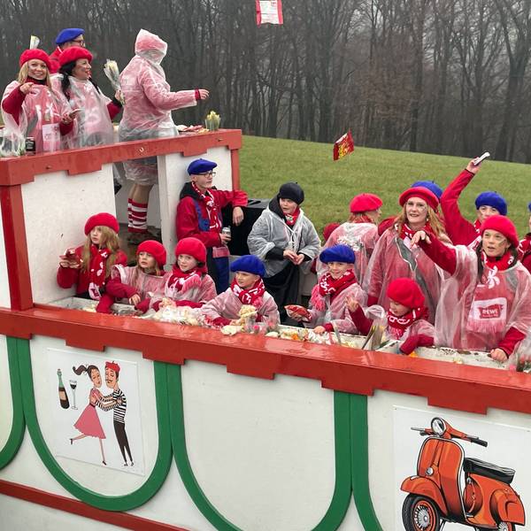 Eine Gruppe jubelt auf einem Karnevalswagen.