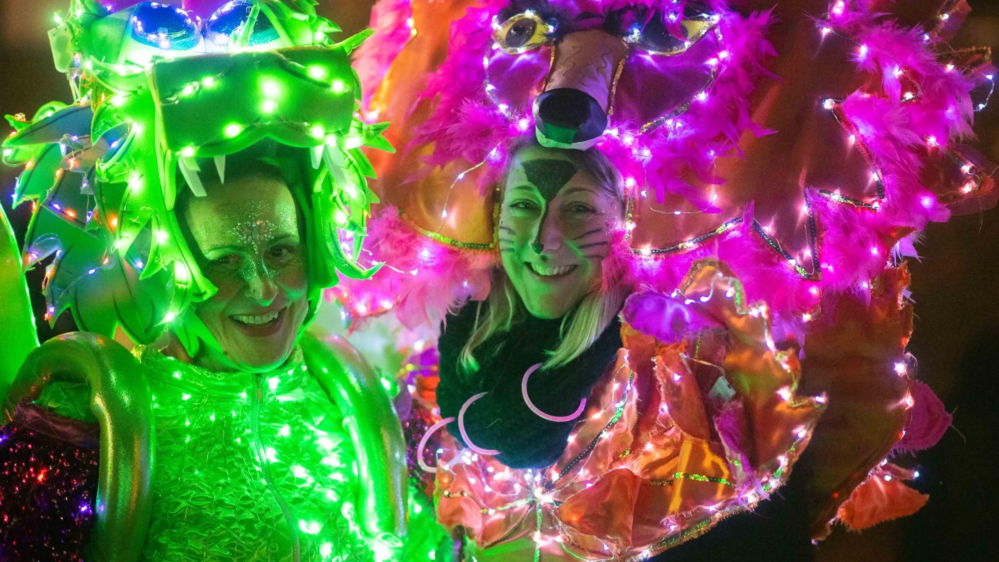 Mit unzähligen LED-Lichtern sind die Kostüme der beiden Frauen in Eiserfey verziert: Eine ist als grüner Drache verkleidet, die andere als pinker Panther.