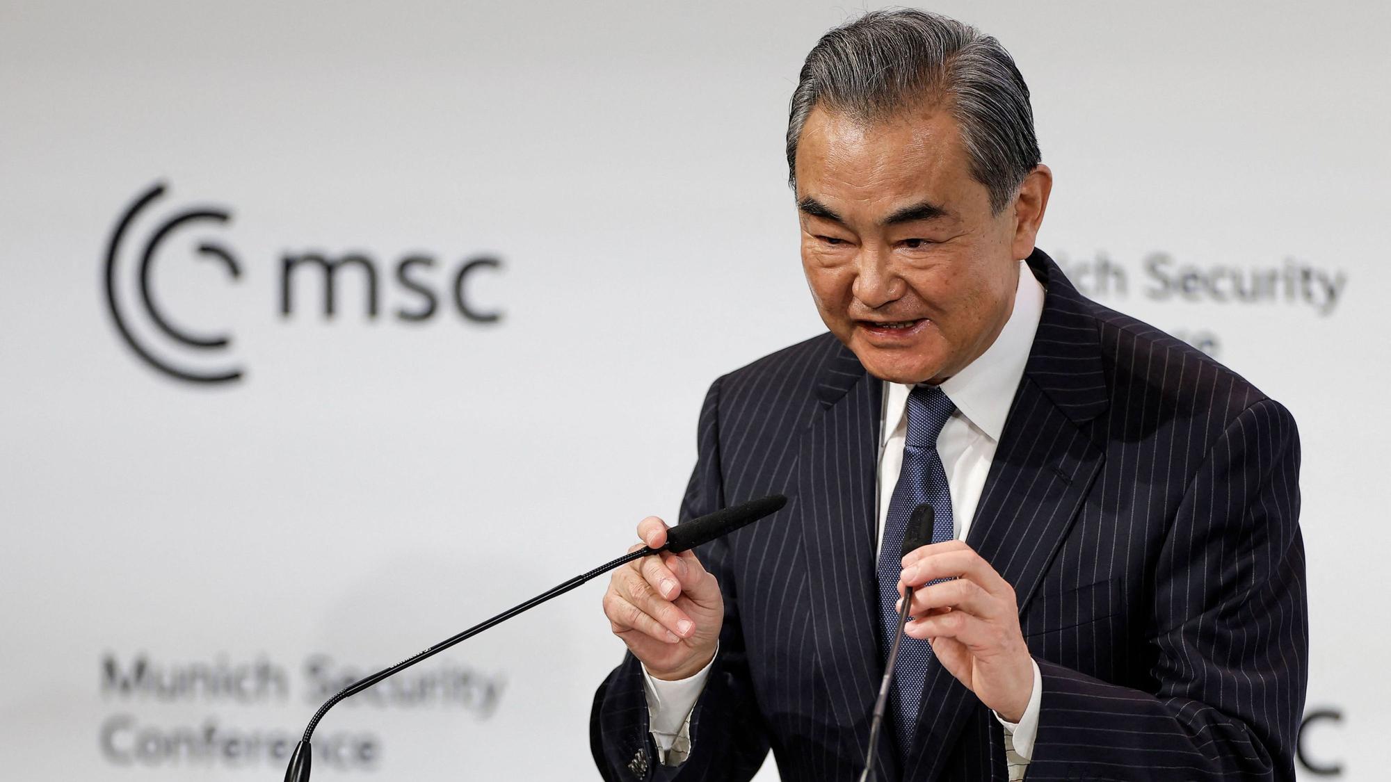 Der oberste chinesische Außenpolitiker Wang Yi spricht auf der Münchener Sicherheitskonferenz und richtetet die Mikrophone zu seinem Gesicht.