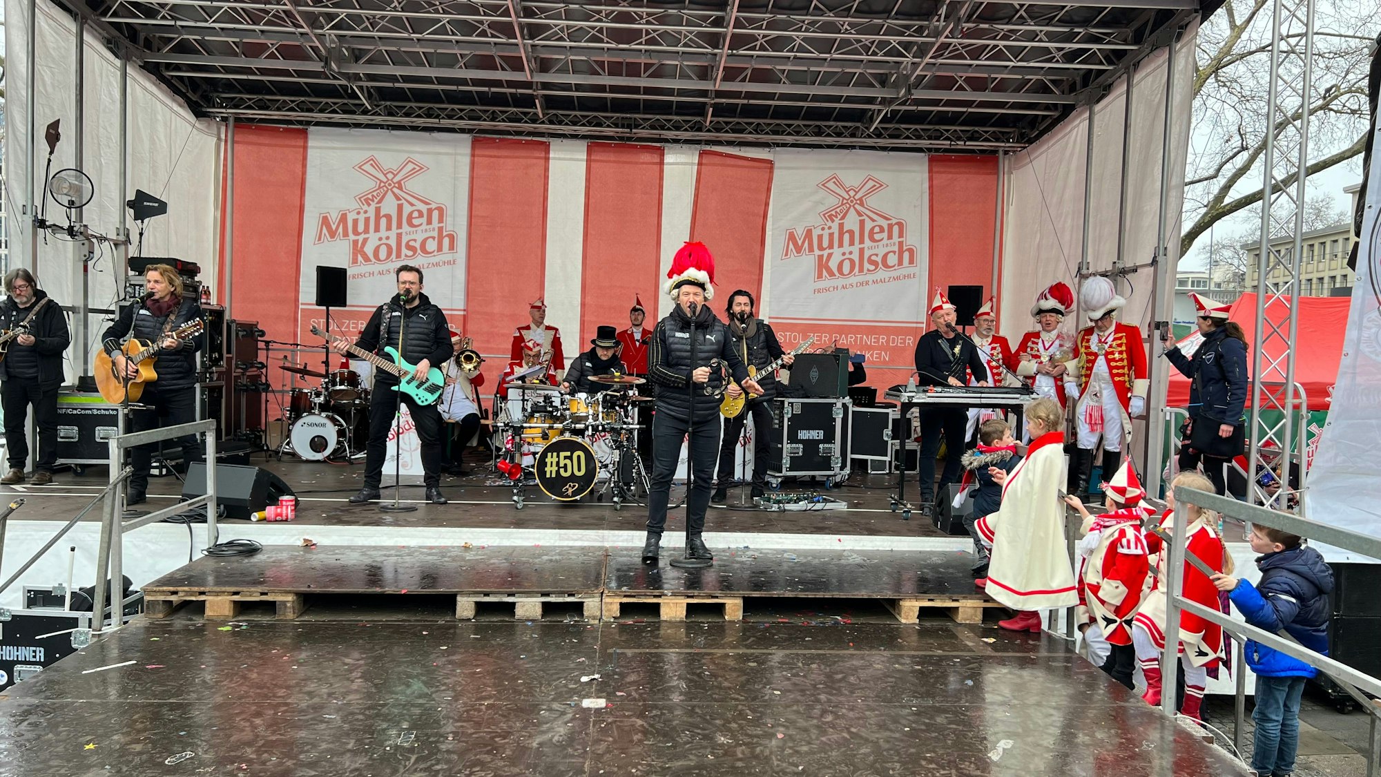Eine Band aus sechs Männern singt auf einer Bühne.