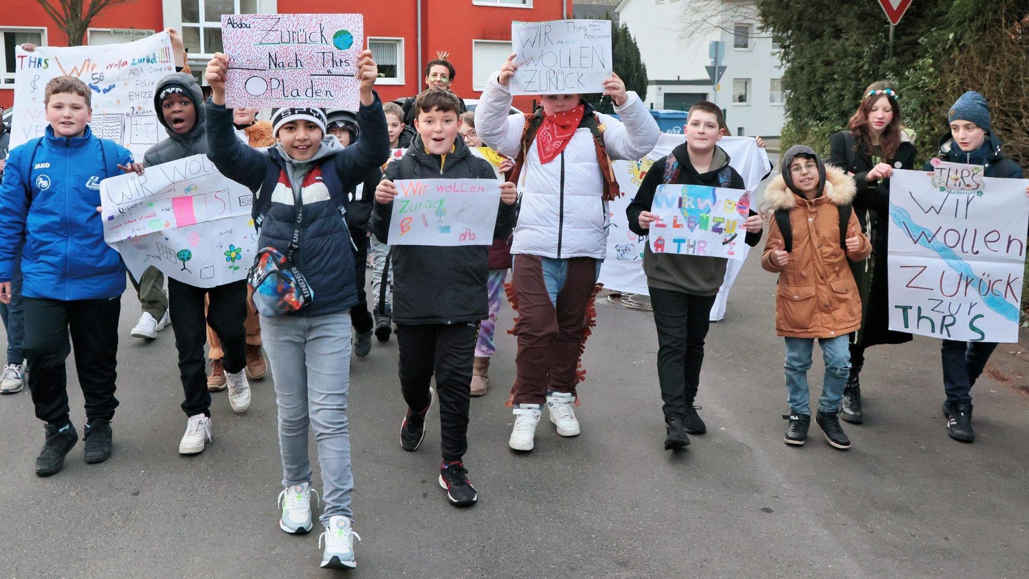 Schülerinnen und Schüler mit selbstgebastelten Plakaten auf der Straße.