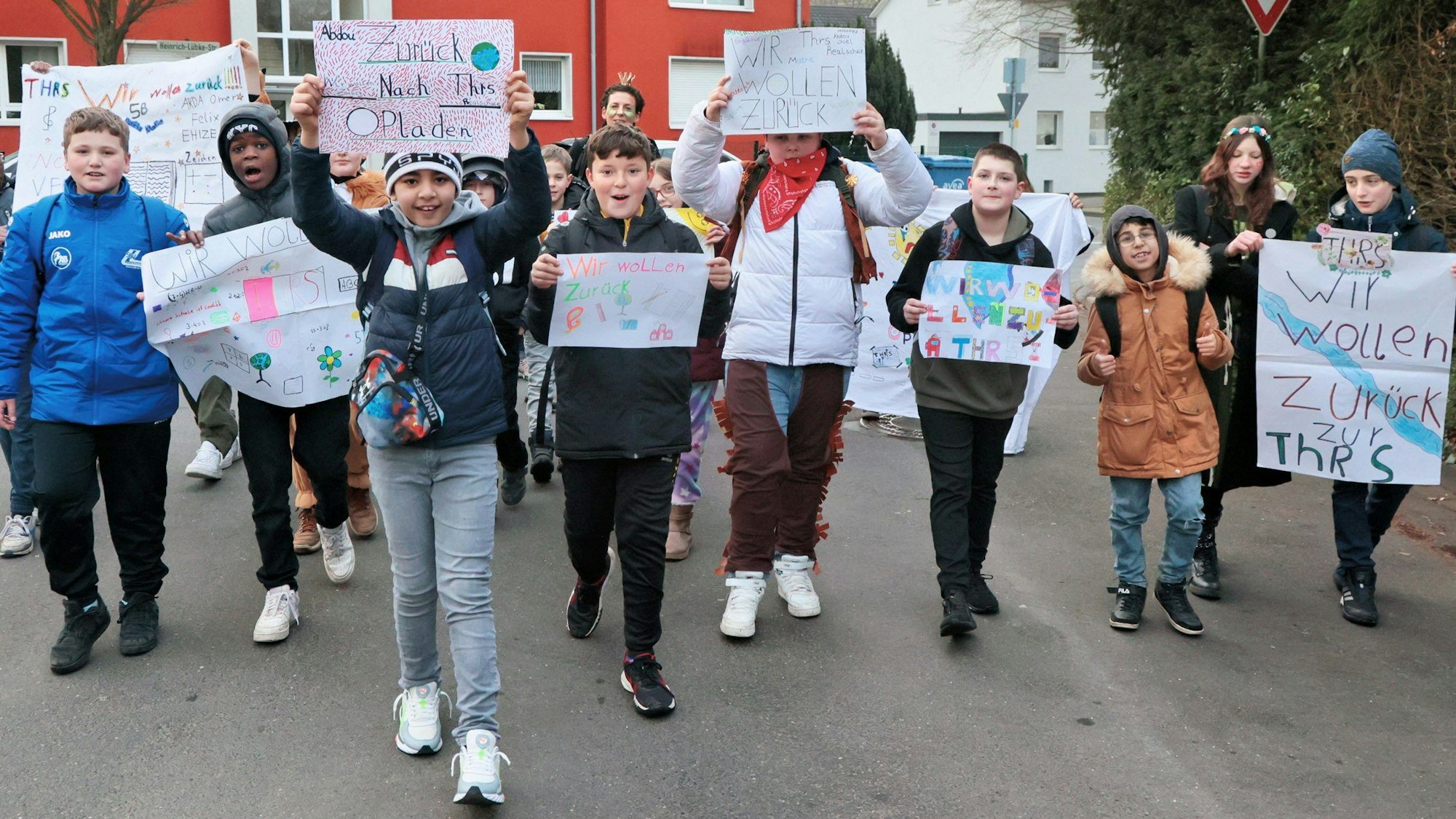 Schülerinnen und Schüler mit selbstgebastelten Plakaten auf der Straße.