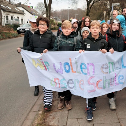 Schüler mit einem Banner: Wir wollen endlich in unsere Schule zurück!