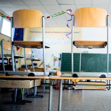 Ein Schulraum mit Stühlen, die auf die Pulte gestellt sind.