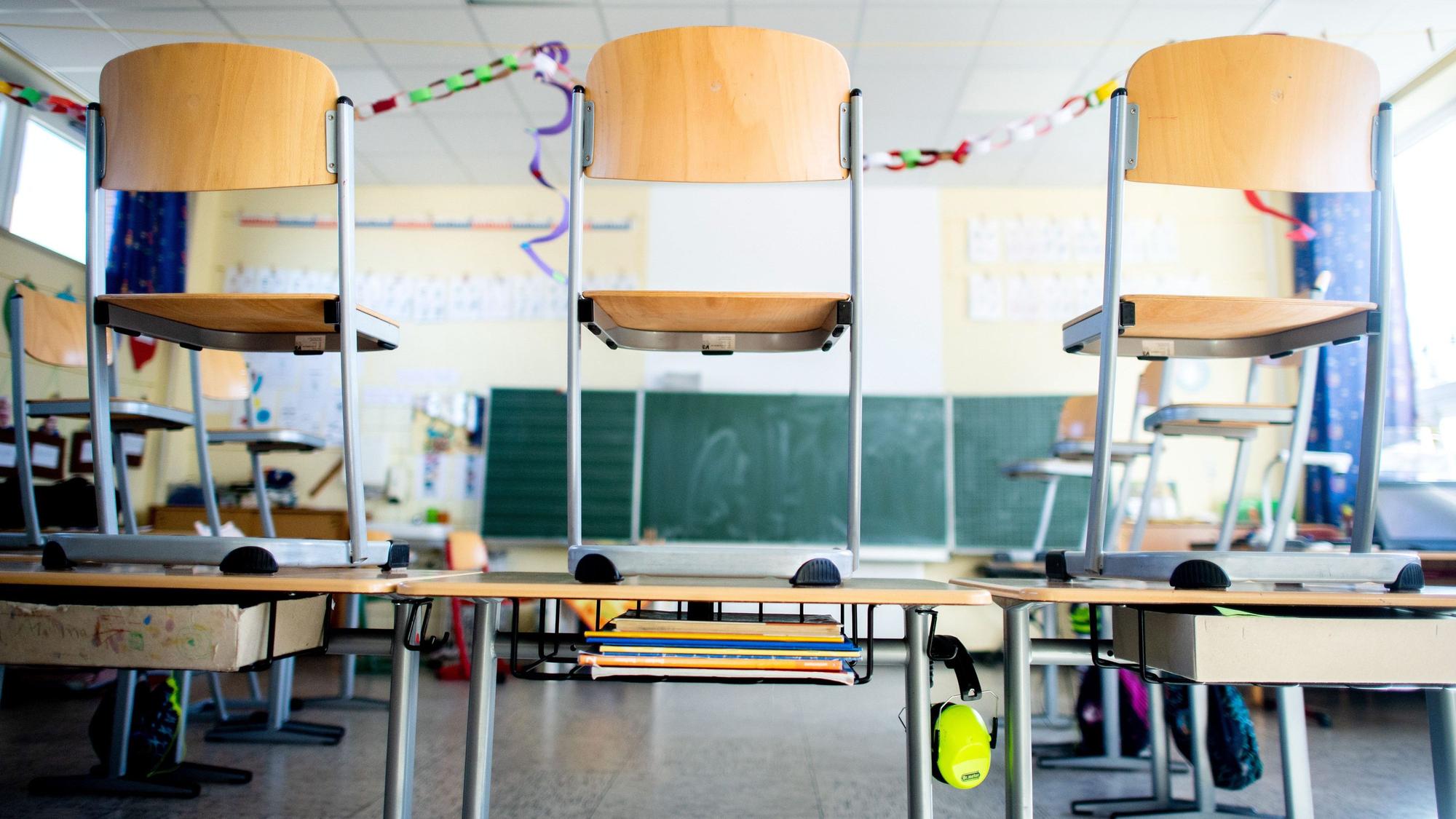 Ein Schulraum mit Stühlen, die auf die Pulte gestellt sind.