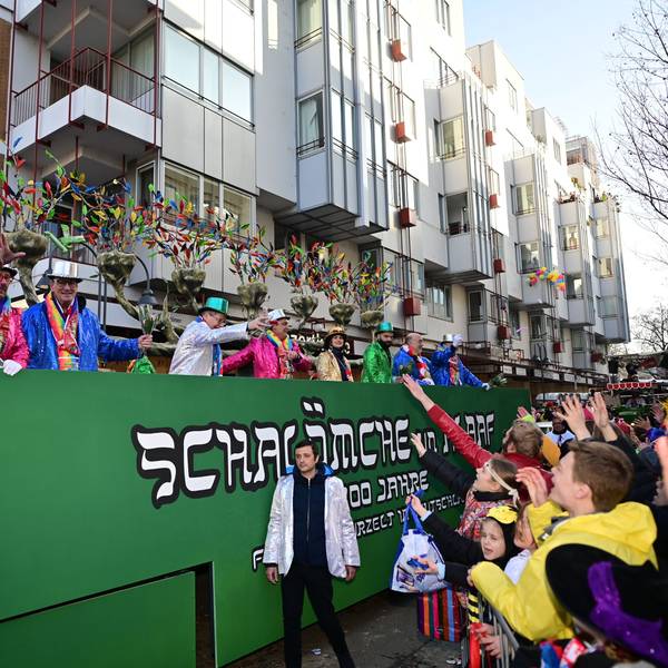 Das Bild zeigt einen Festwagen, der in Grün gehalten ist. Auf der Seite steht „Schalömche un Alaaf“.