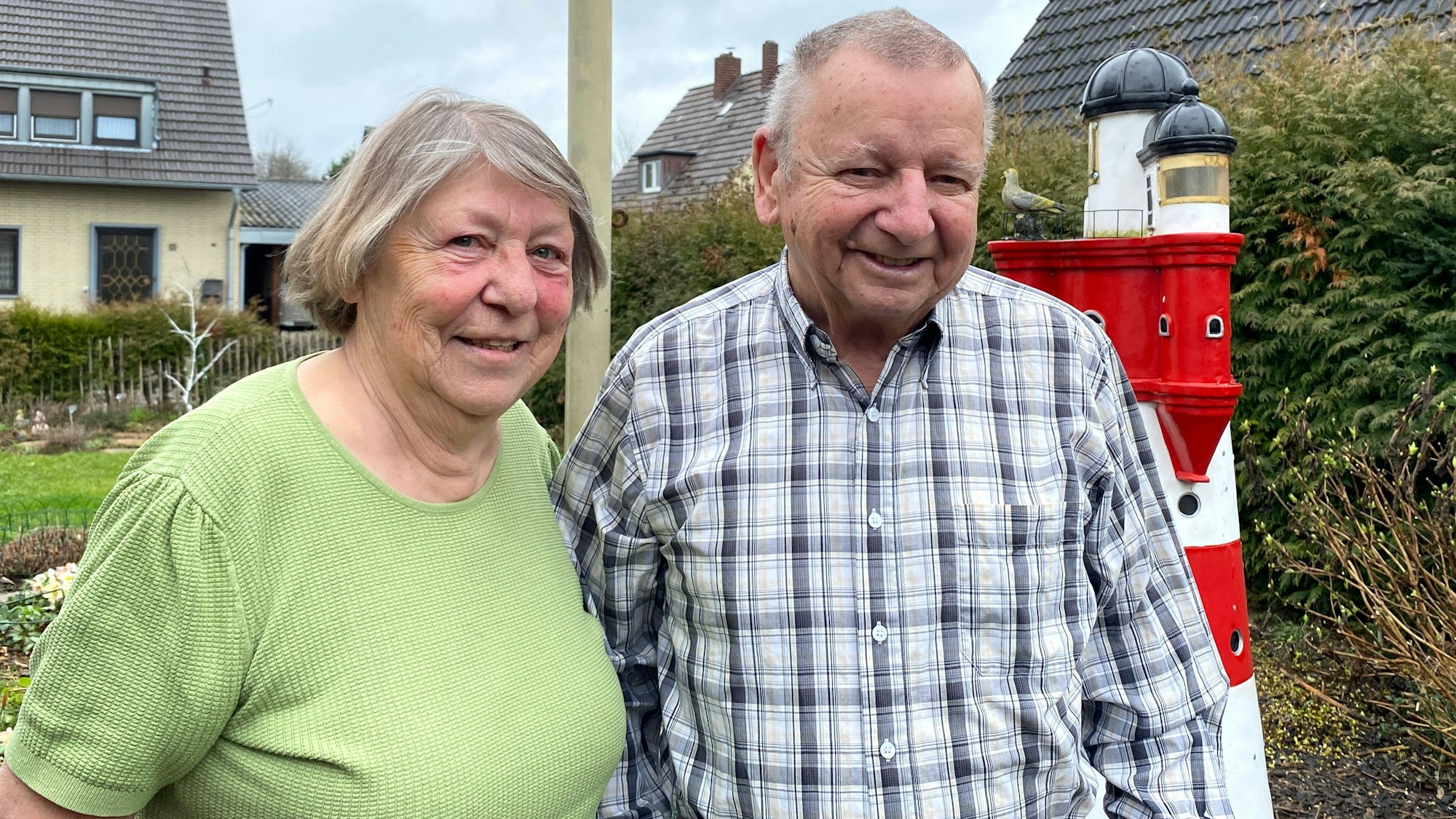Ein Ehepaar steht nebeneinander lachend Im Garten