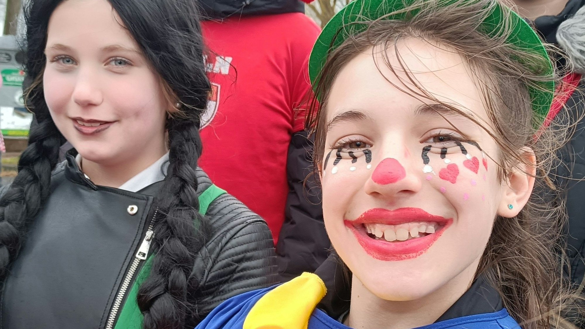 Ein Mädchen ist als Clown verkleidet und lacht in die Kamera.