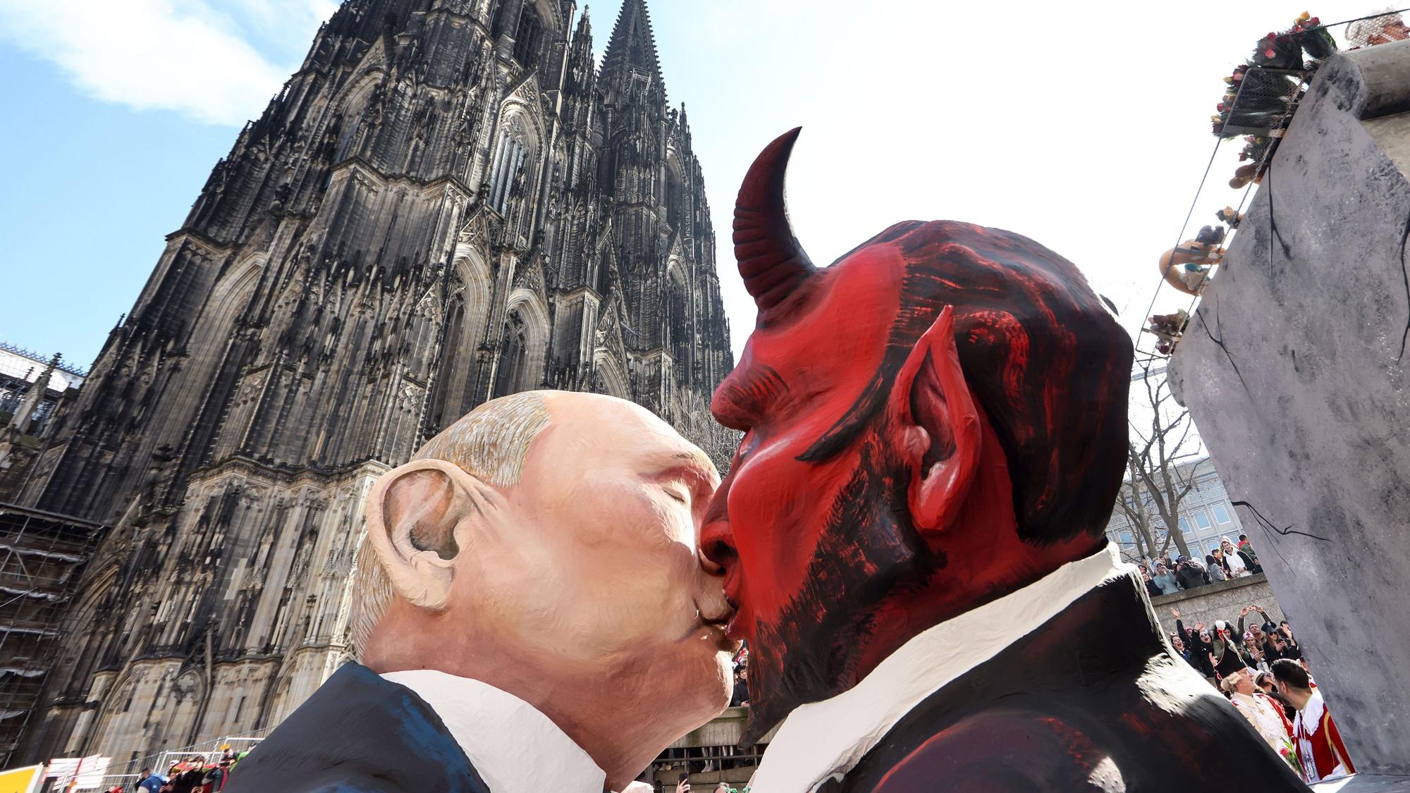 Der Mottowagen „Verkörperte Zitate“, dem Motto der Session von 1911, mit einer Darstellung des russischen Präsidenten Putin, der den Teufel küsst, fährt am Kölner Dom vorbei.