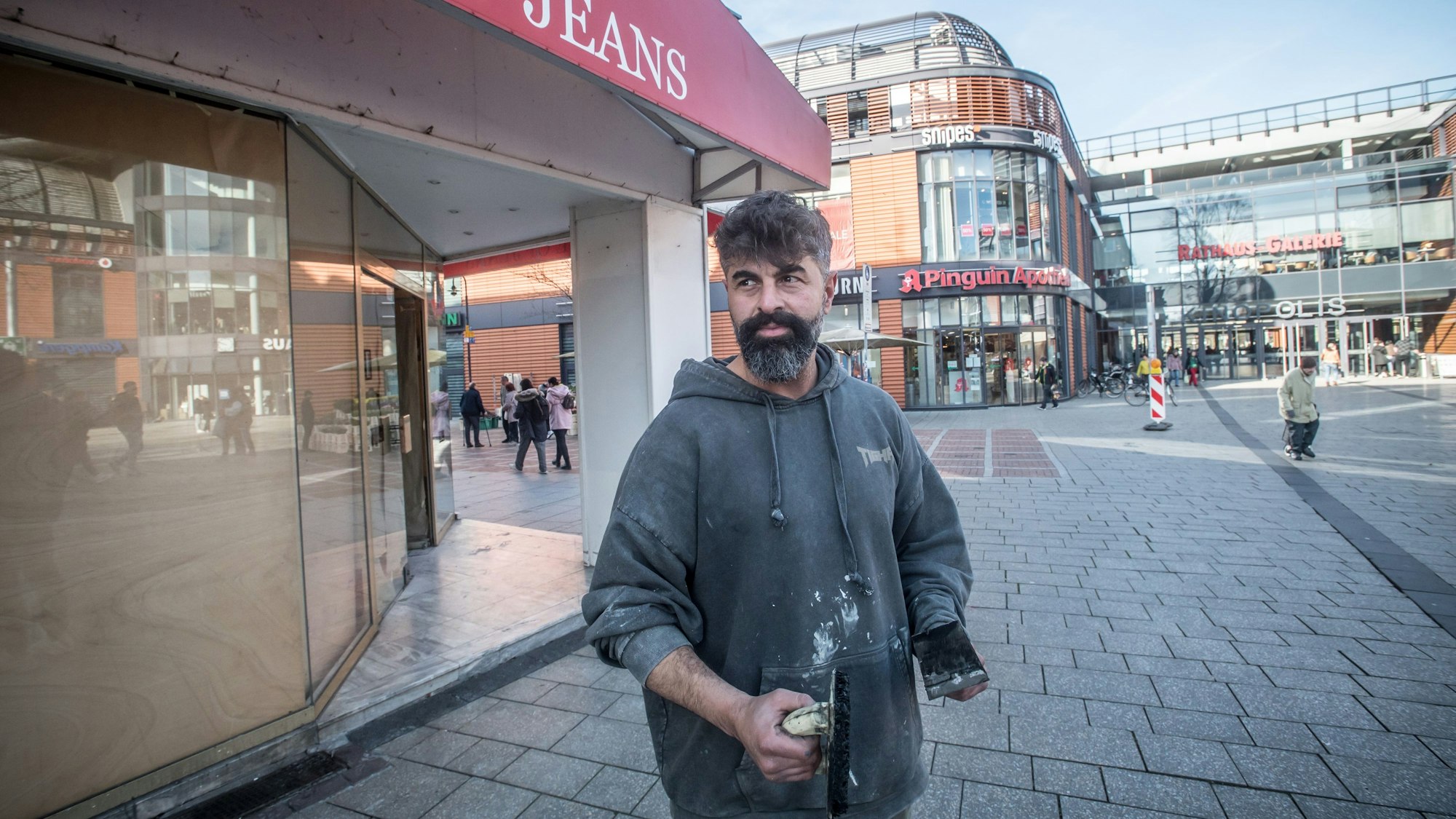 Deniz Gözen steht in Arbeitskleidung vor dem Ladenlokal von House of Jeans.
