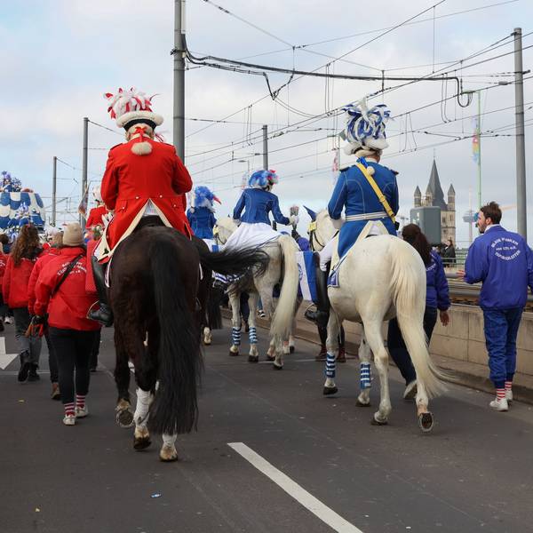 Karnevalisten reiten auf ihren Pferden über die Deutzer Brücke.