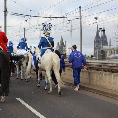 Karnevalisten reiten auf ihren Pferden über die Deutzer Brücke.