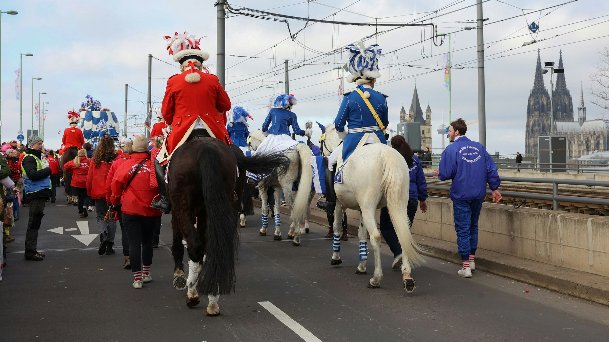 Karnevalisten reiten auf ihren Pferden über die Deutzer Brücke.