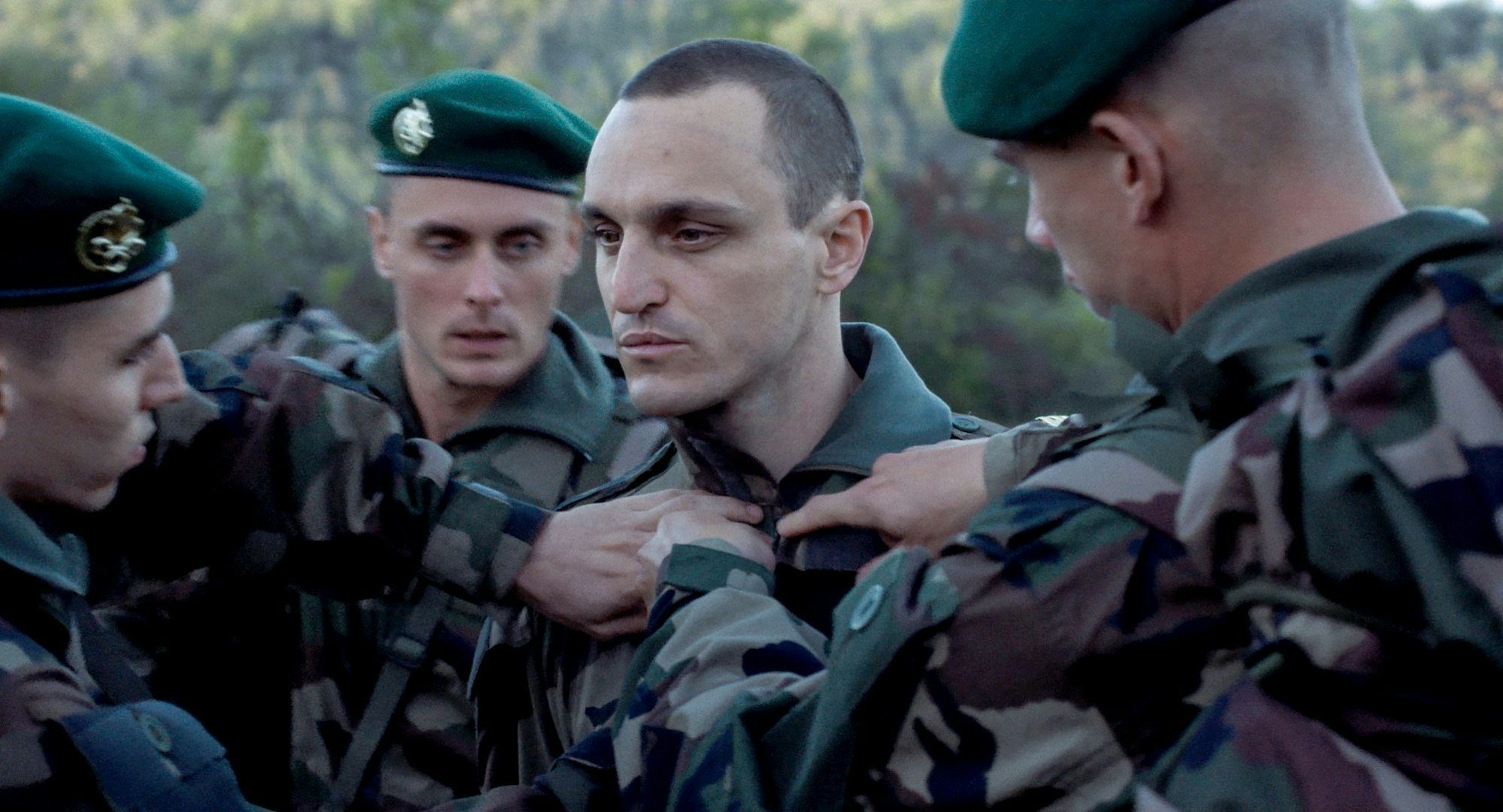 Franz Rogowski hat einen apathischen Blick, drei Soldaten stehen nah um ihn. Alle tragen Tarnkleidung.