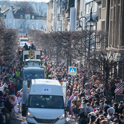 Wagen des Rosenmontagszugs in Euskirchen fahren durch die Wilhelmstraße. Links und rechts stehen zahlreiche Besucher.