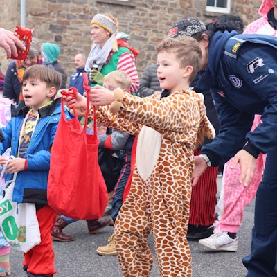 Zuschauer erwarten am Straßenrand Kamelle bei einem Karnevalsumzug.
