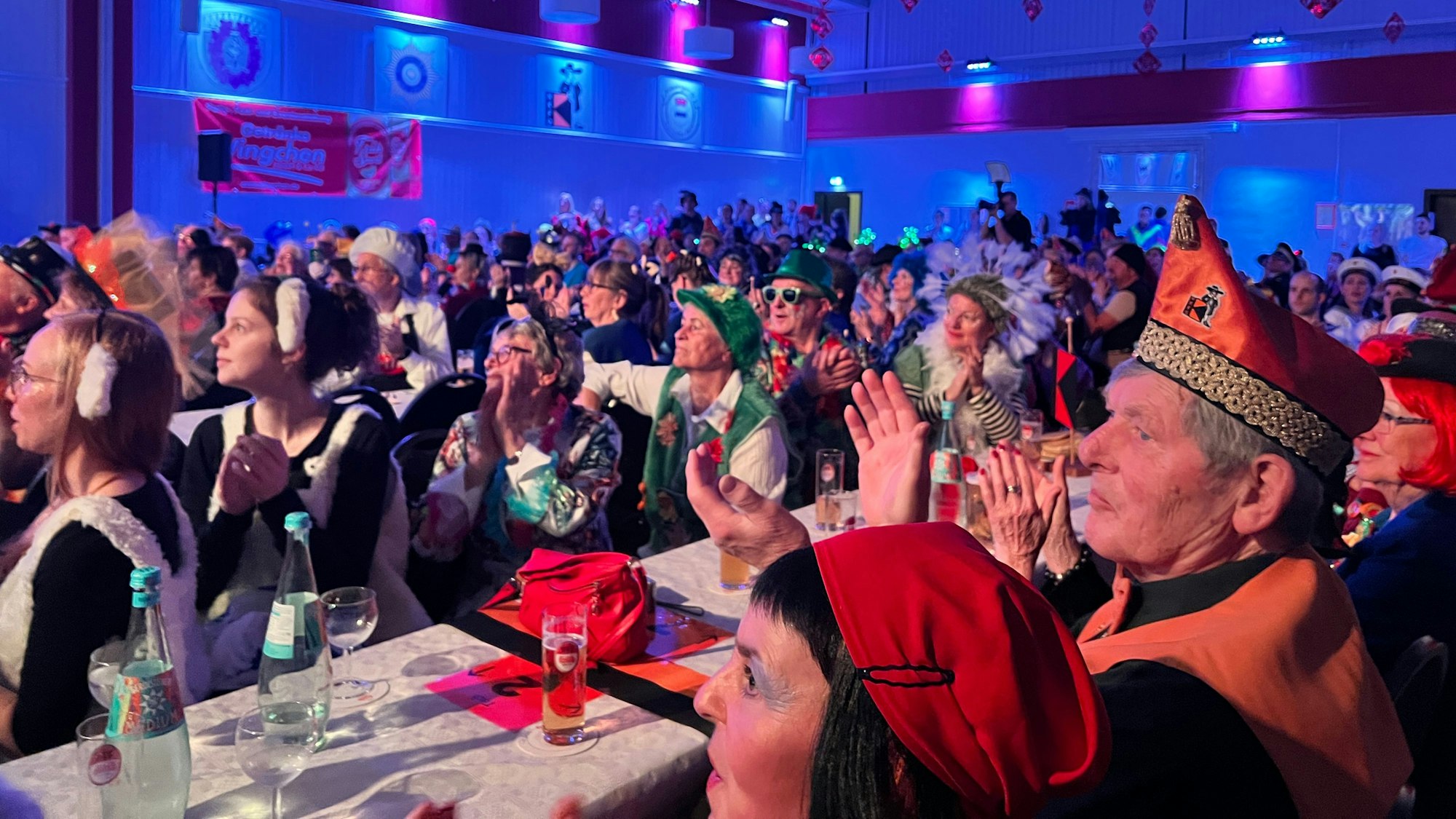 Voll besetzte Festhalle mit applaudierenden und verkleideten Karnevalistinnen und Karnevalisten.