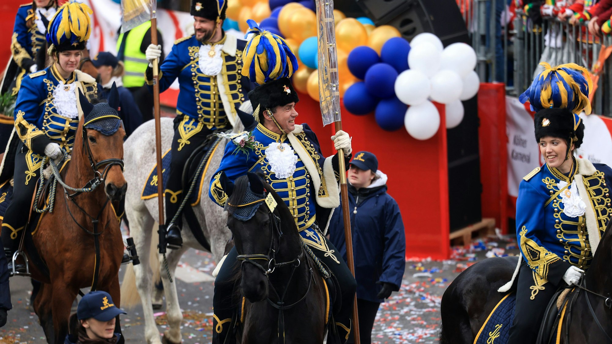 Reiter auf Pferden laufen im Rosenmontagszug mit.