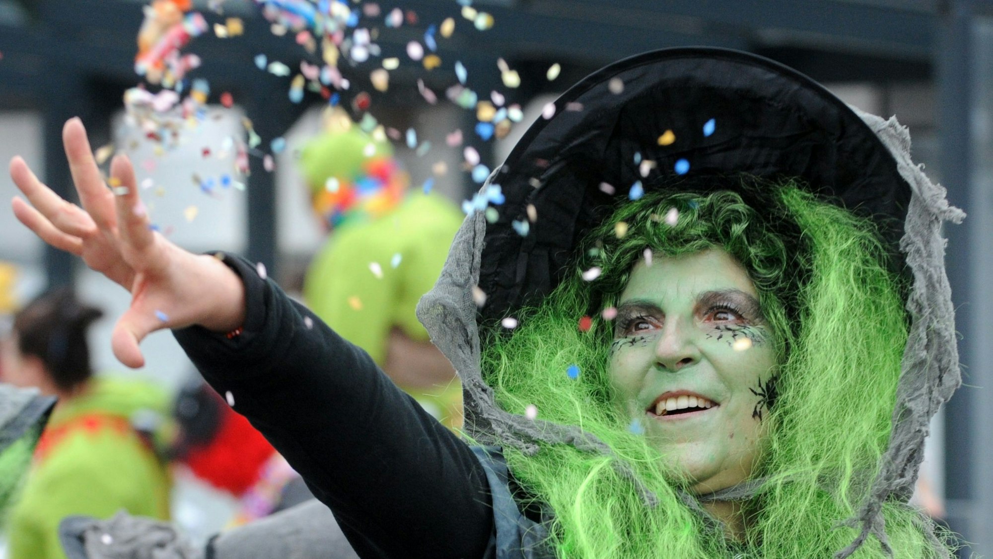 Zu sehen ist eine kostümierte Frau, die Konfetti wirft.