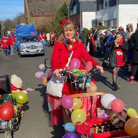Eine bunt verkleidete Karnevalistin fährt mit ihrem Lastenrad im Zug mit.
