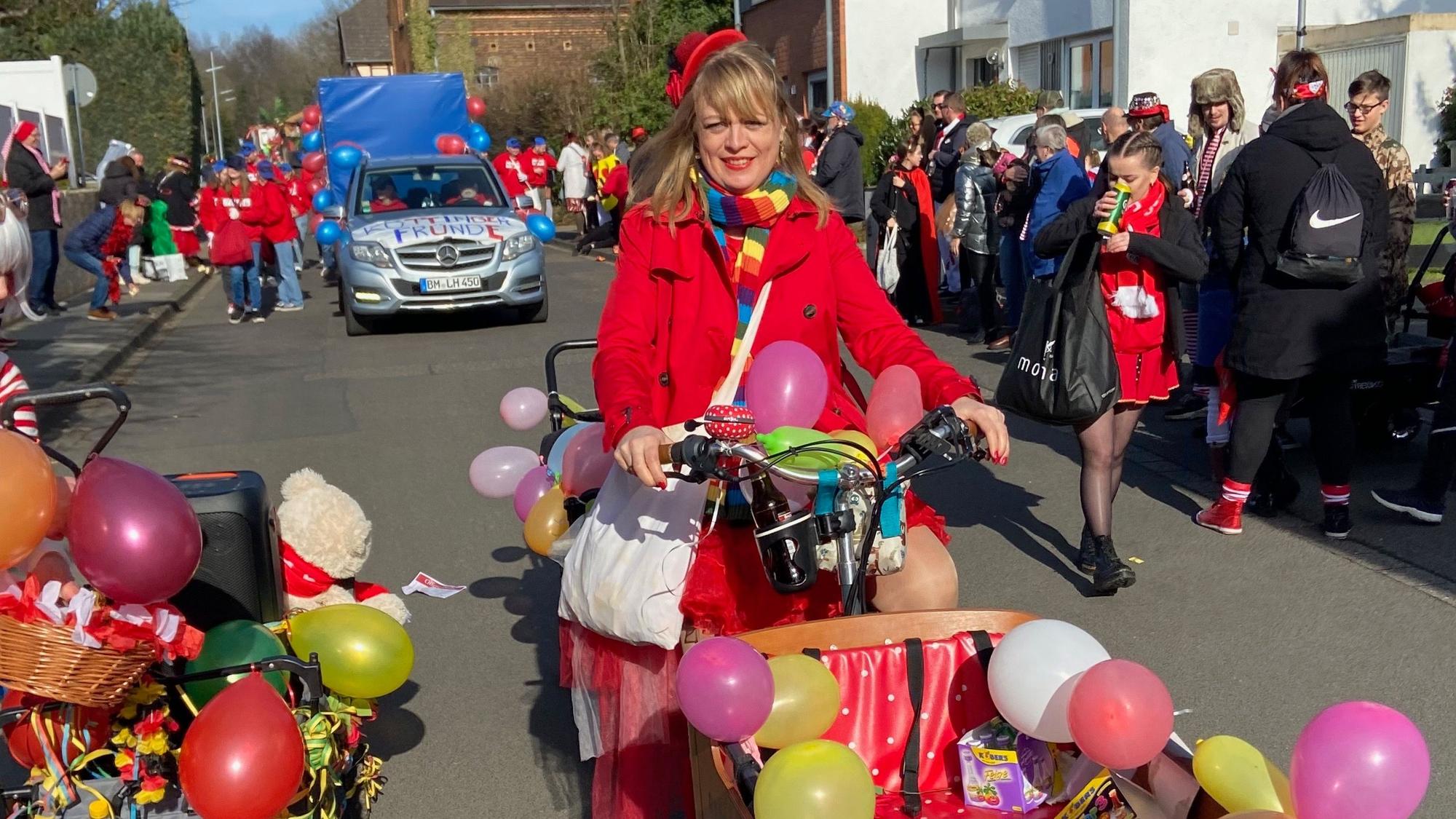 Eine bunt verkleidete Karnevalistin fährt mit ihrem Lastenrad im Zug mit.