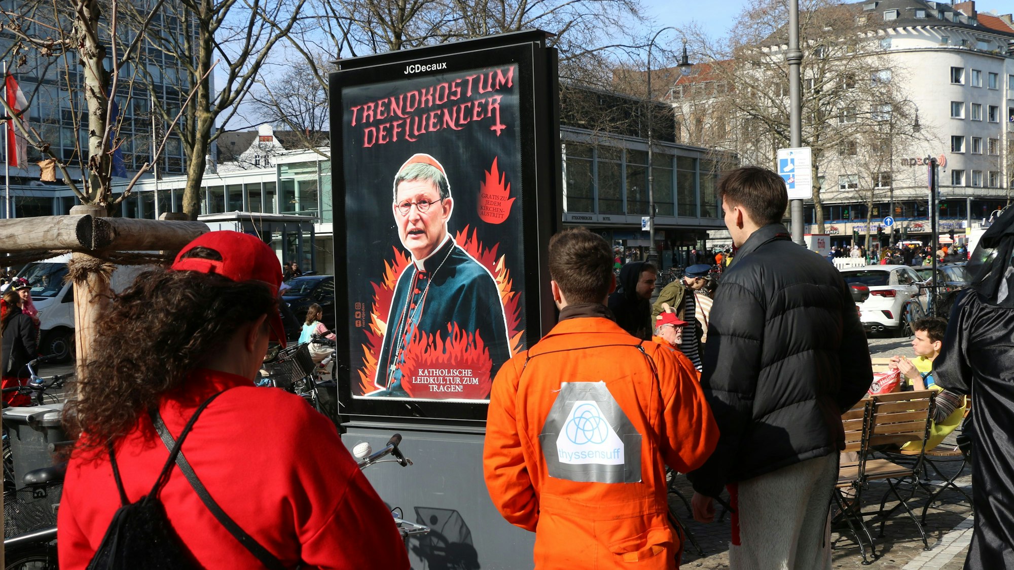 Personen beobachten die Protest-Plakate, die am Rosenmontag in Köln aufgetaucht sind.