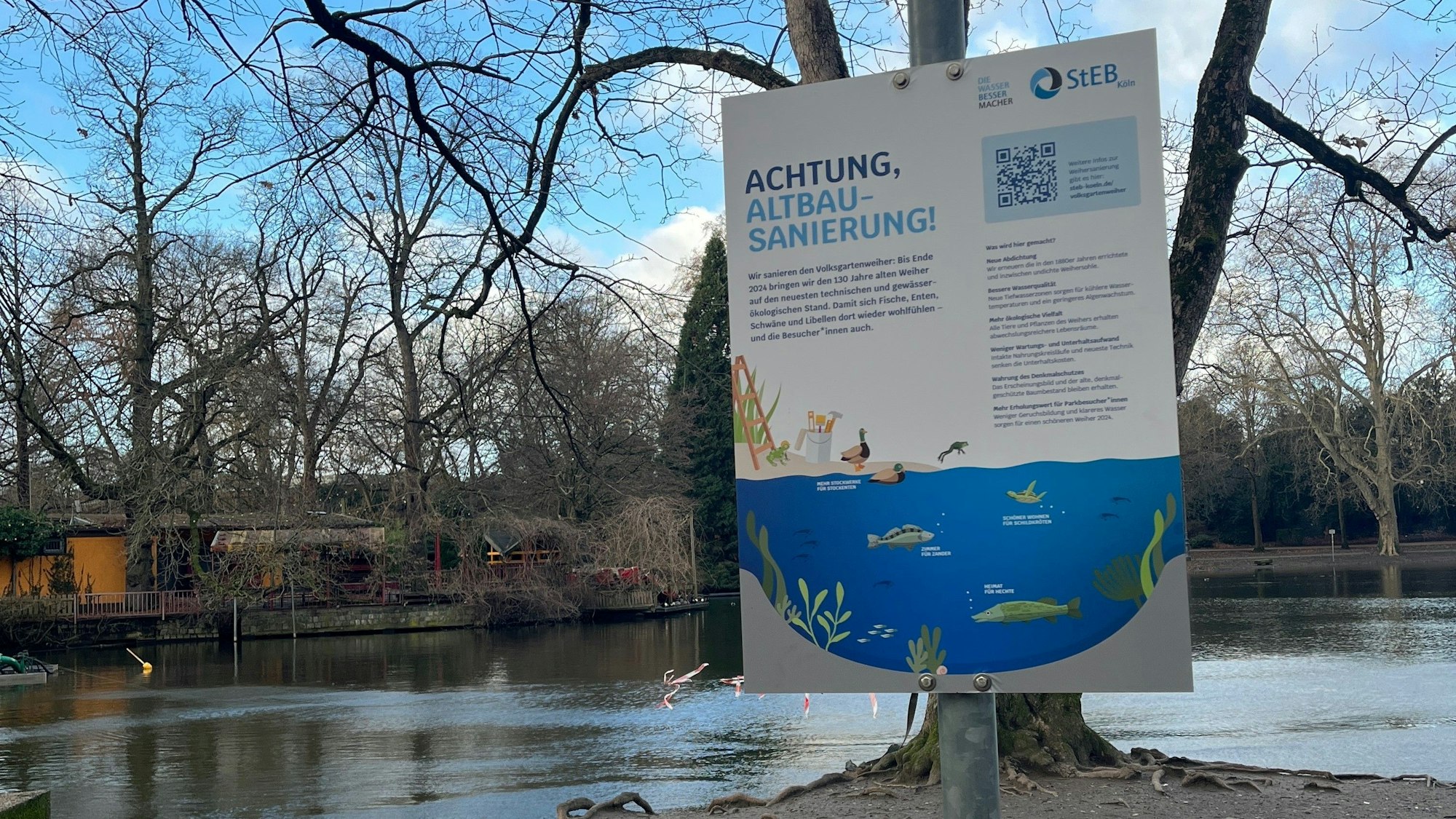 Ein Metallschild steht vor einem Teich.